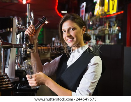 Happy barmaid pulling a pint of beer in a bar
