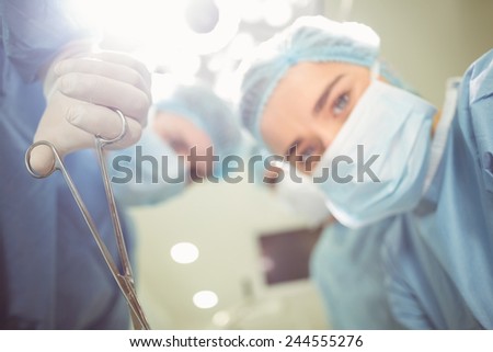 Young surgeons looking down at camera holding clamp at the university