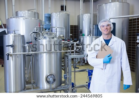 Man holding a clipboard standing in front of the container in the factory