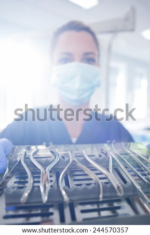 Dentist in blue scrubs showing tray of tools at the dental clinic