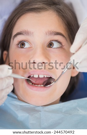 Dentist using dental explorer and angled mirror in mouth open of a patient