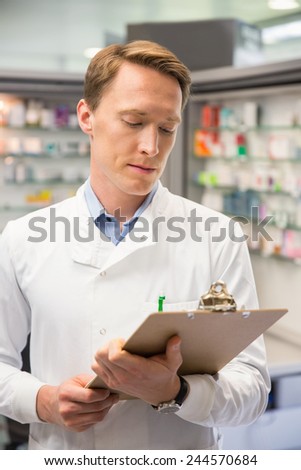 Focused pharmacist writing on clipboard at the hospital pharmacy