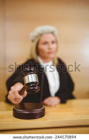 Serious judge with a gavel wearing robes and wig in the court room