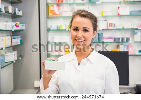 Junior pharmacist showing medicine box at the hospital pharmacy
