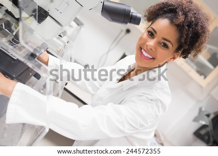 Pretty science student using microscope at the university
