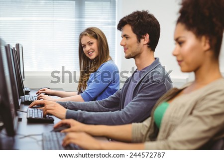 Happy student in computer class smiling at camera at the university