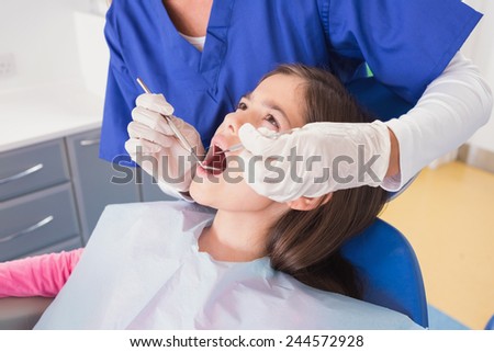 Pediatric dentist doing examination at a scared young patient in dental clinic