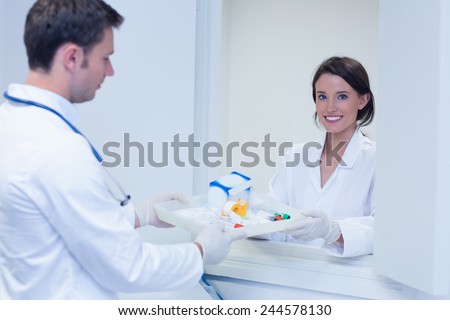 Portrait of a smiling woman taking tray with blood samples in hospital