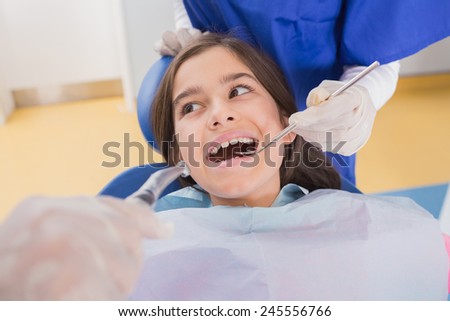 Dentist and his dental assistant examining a young patient in dental clinic