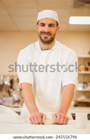 Baker kneading dough at a counter in a commercial kitchen