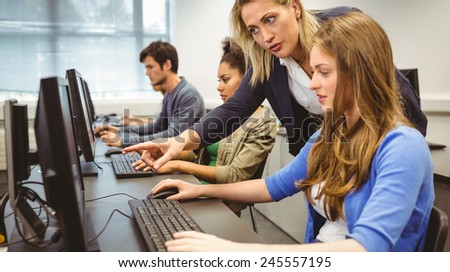 Attractive teacher helping her student in computer class at the university