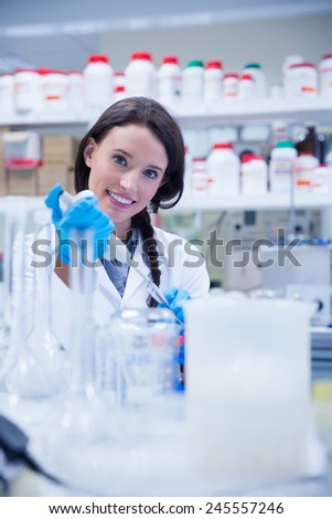 Smiling female scientist using a pipette in hospital