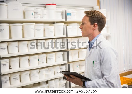 Handsome pharmacist looking at medicine at the hospital pharmacy