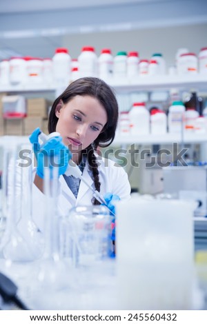 Concentrated female scientist using a pipette in hospital