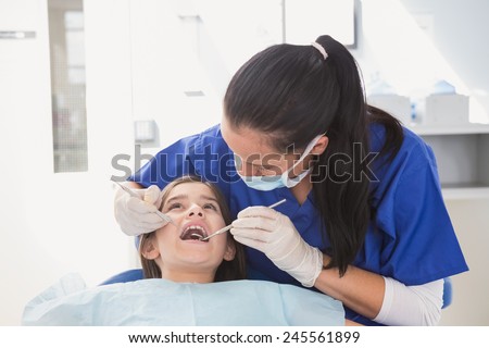 Pediatric dentist using dental explorer and angled mirror in mouth open of a patient