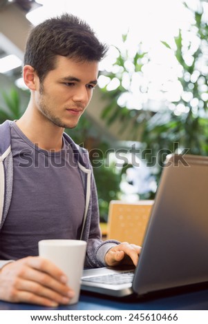 Young student using his laptop in cafe at the university