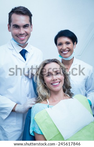 Portrait of happy male dentist with assistant and female patient