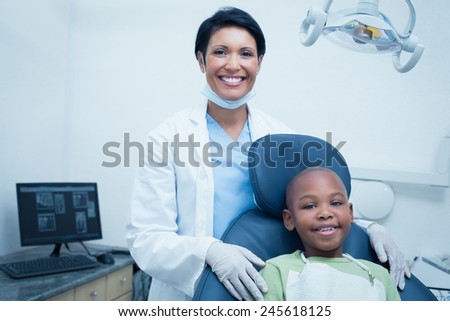 Portrait of female dentist examining boys teeth in the dentists chair