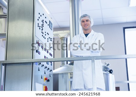Smiling scientist standing with arms crossed in the factory
