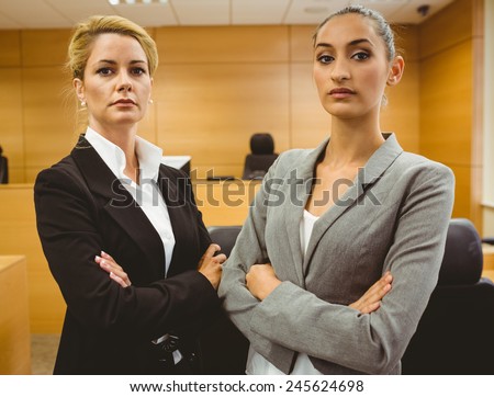 Two serious lawyers standing with arms crossed in the court room