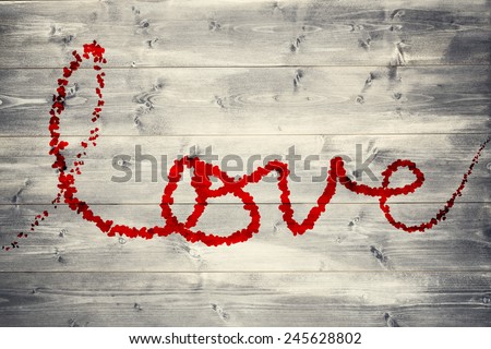 Love spelled out in petals against bleached wooden planks background