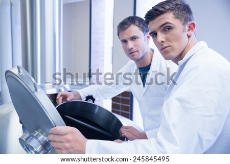 Two scientists opening the lid and looking at the camera in the factory