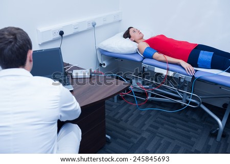 Doctor checking blood pressure of woman at medical office