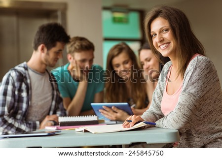 Smiling friends sitting studying and using tablet pc after school for teamwork