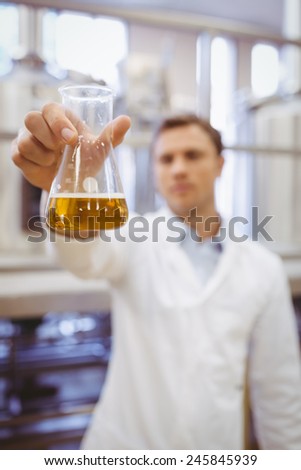 Thoughtful scientist holding a beaker in the factory