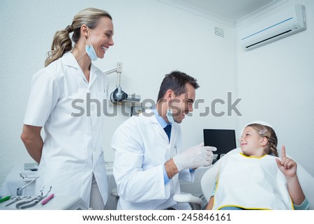 Male dentist and assistant talking to girl in the dentists chair