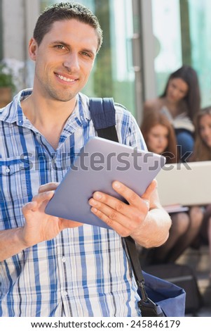 Happy student using his tablet pc on campus at the university