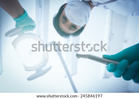 Portrait of female dentist in surgical mask holding dental drill