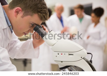 Young medical student working with microscope at the university