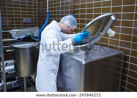 Man in lab coat looking into the machine in the factory