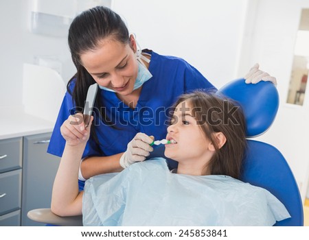 Pediatric dentist brushing teeth to her young patient in dental clinic