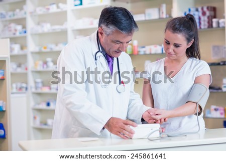 Pharmacist showing blood pressure of his patient to her in the pharmacy