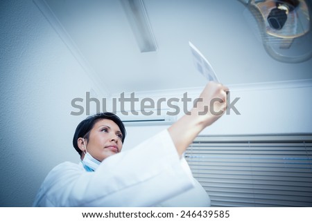 Low angle view of concentrated young female dentist looking at x-ray