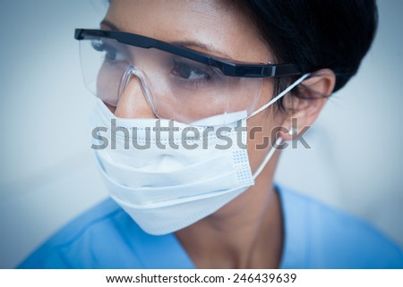 Close up of female dentist wearing surgical mask and safety glasses