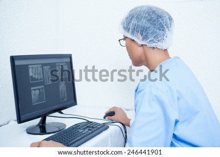 Concentrated female dentist looking at x-ray on computer