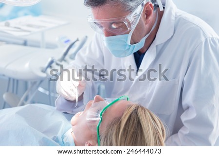 Dentist in surgical mask and gloves holding tool at the dental clinic