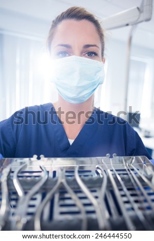 Dentist in blue scrubs showing tray of tools at the dental clinic