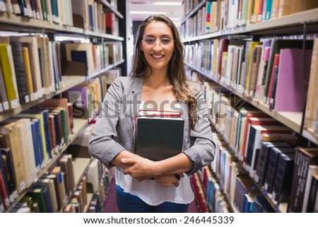 Pretty student picking out a book in library at the university