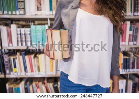 Pretty student holding books in library at the university
