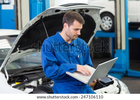 Mechanic using his laptop at the repair garage