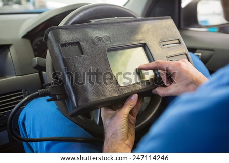 Mechanic using diagnostic tool in the car at the repair garage
