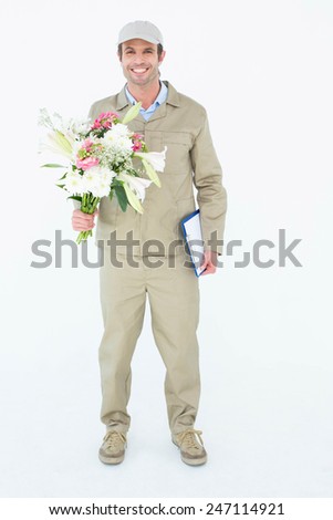 Full length portrait of happy delivery man holding bouquet and clipboard against white background
