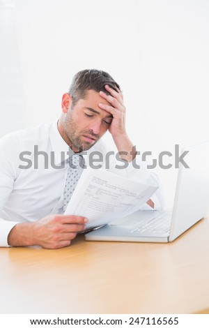 Confused businessman looking at his paper in his office