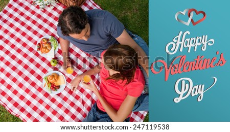 Elevated view of two friends lying on a blanket with a picnic against cute valentines message