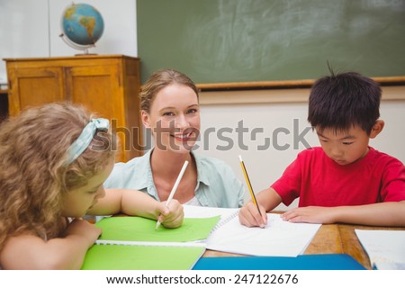 Pretty teacher helping pupil in classroom at the elementary school