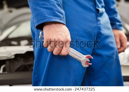 Mechanic standing with wrench in hand at the repair garage